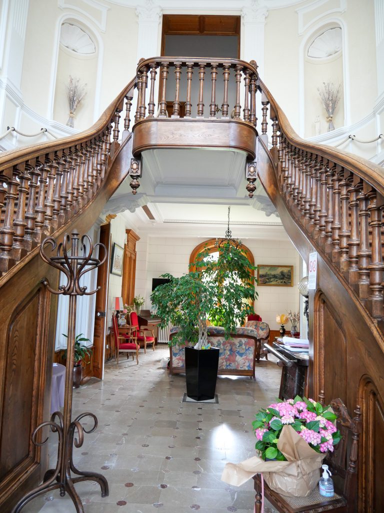 Dès le hall d'entrée, le regard est naturellement attiré par le majestueux escalier d'honneur à double volée. Véritable signature architecturale du Château des Marronniers, il structure les volumes de la demeure et accompagne les visiteurs vers les chambres dans une mise en scène élégante.